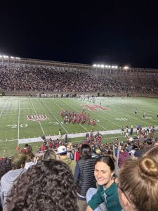 Image of a Harvard football game as seen from the stands, with players walking across the field.