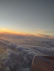 View of the sky and clouds from the window of an airplane with a pretty sunset in the background