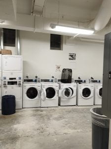 Room filled with washing machines with a concrete floor.