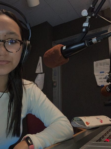 Tenzin sitting with headphones on in front of a studio microphone.