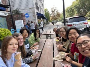 Group of students sitting at a picnic table outside eating ice cream