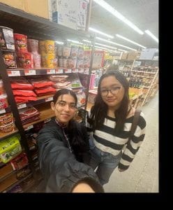 Image of Tenzin and a friend in front of shelves in a grocery store while shopping for ramen.