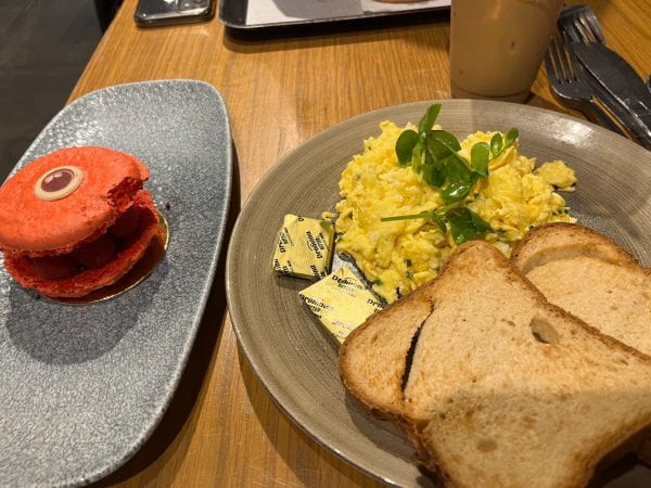 Image of toast, eggs, and a red macaron on two plates in a restaurant.