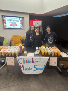 Members of the Chamber Music Society standing with a table where they are selling boba.