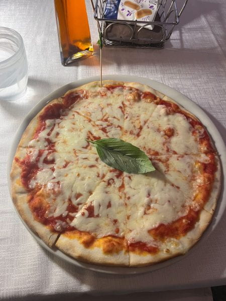 A personal-size pizza garnished with a single basil leaf on top.