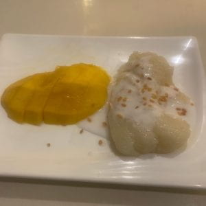 Image of a rectangular white plate with mango sticky rice.
