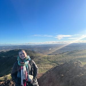 Image of Anna standing atop a high plateau with a wide view of the surrounding countryside.