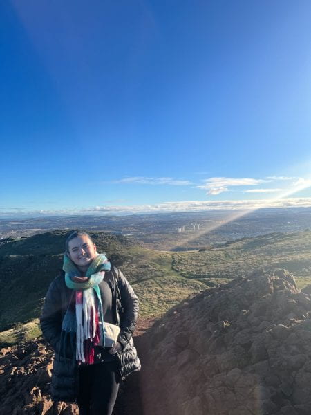 Image of Anna standing atop a high plateau with a wide view of the surrounding countryside.