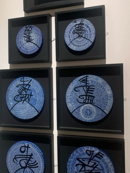 Image of artwork featuring blue and white glazed plates with lettering.