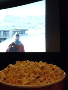 A bowl full of popcorn in front of a movie screen
