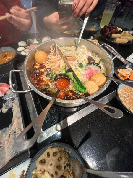 Steaming food in a large pot between bowls of different foods.