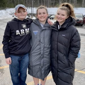 Image of Anna and her brother and sister standing in a parking lot after a game.