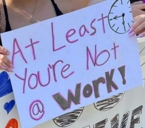 Sign reading "At least you're not @ work!"