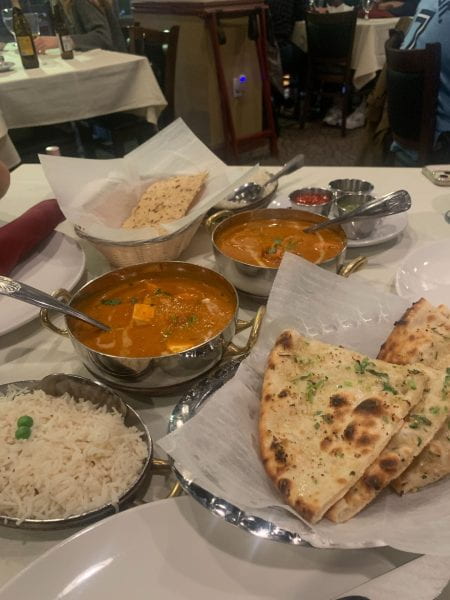 A table full of various Indian dishes including naan, rice, and curry.